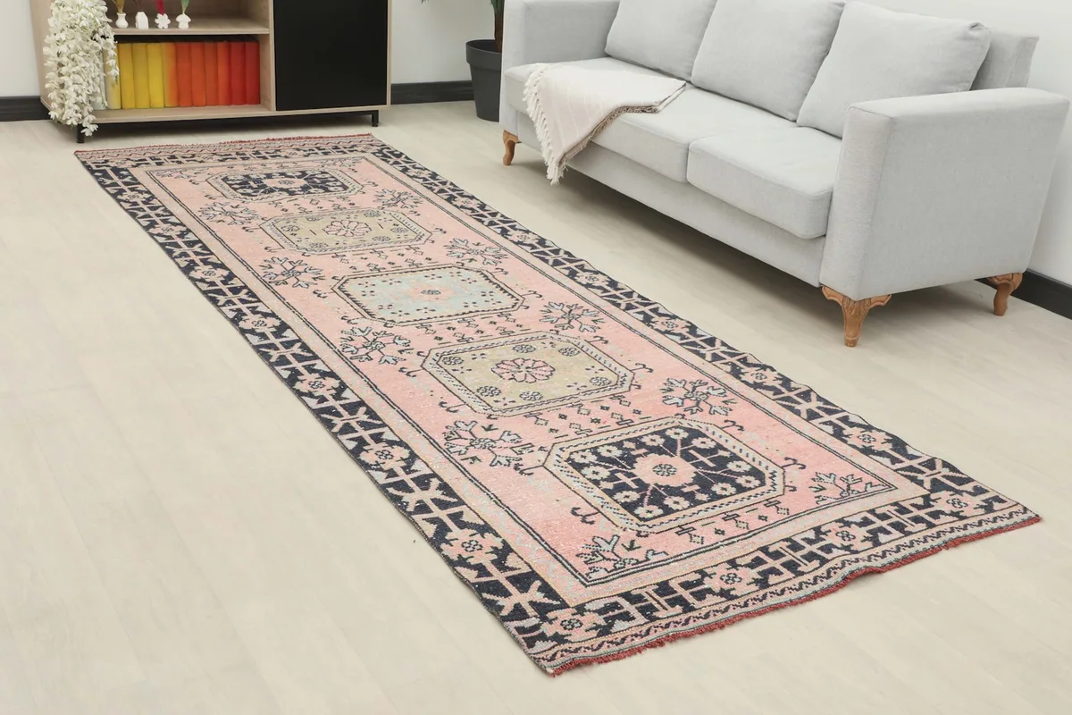 Angled view of the vintage pink runner in a room, showing its length and design alongside a sofa