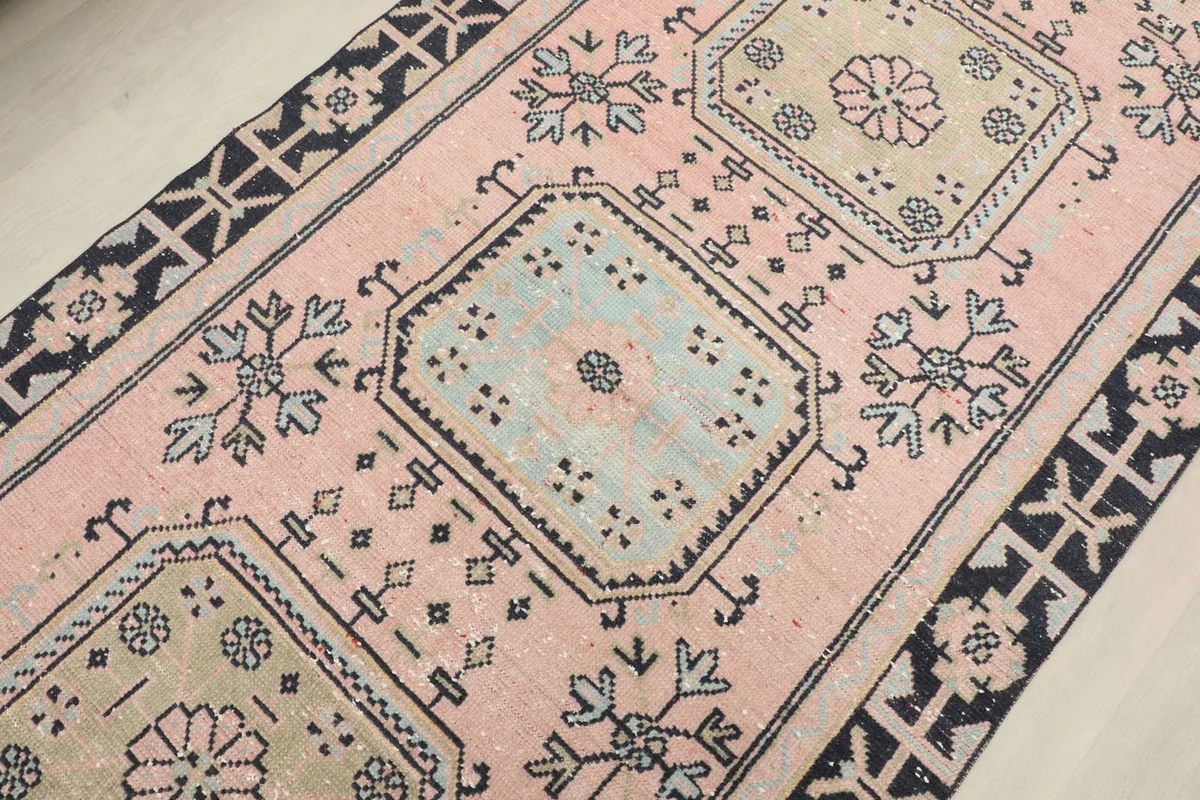 Detailed view of the central geometric motifs in pink, navy, beige, and light blue