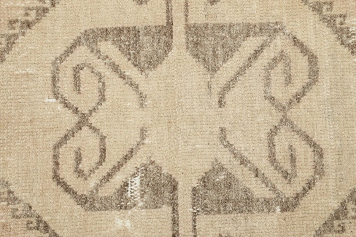 Macro shot of the intricate gray geometric pattern against the beige wool pile