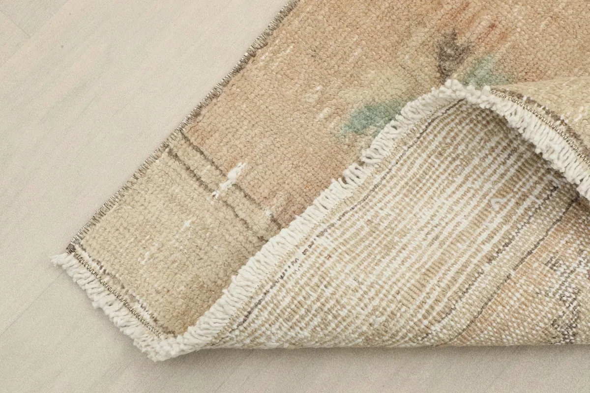 Corner of the rug folded back to show the hand-knotted wool pile and cotton foundation