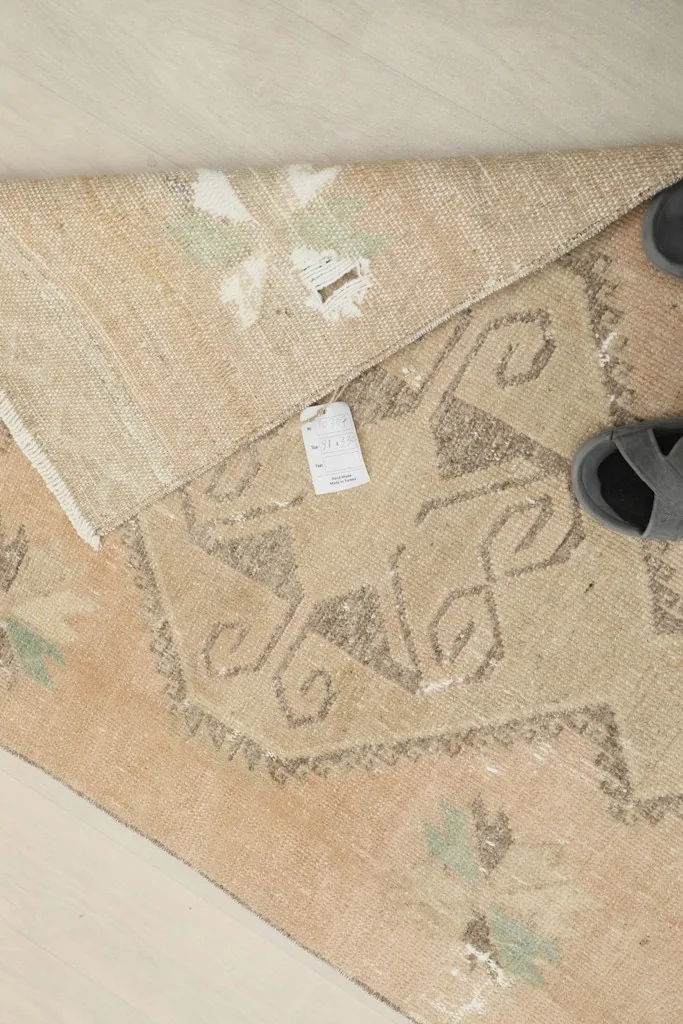 Overhead view of a folded section of the rug, showing a tag and part of the pattern