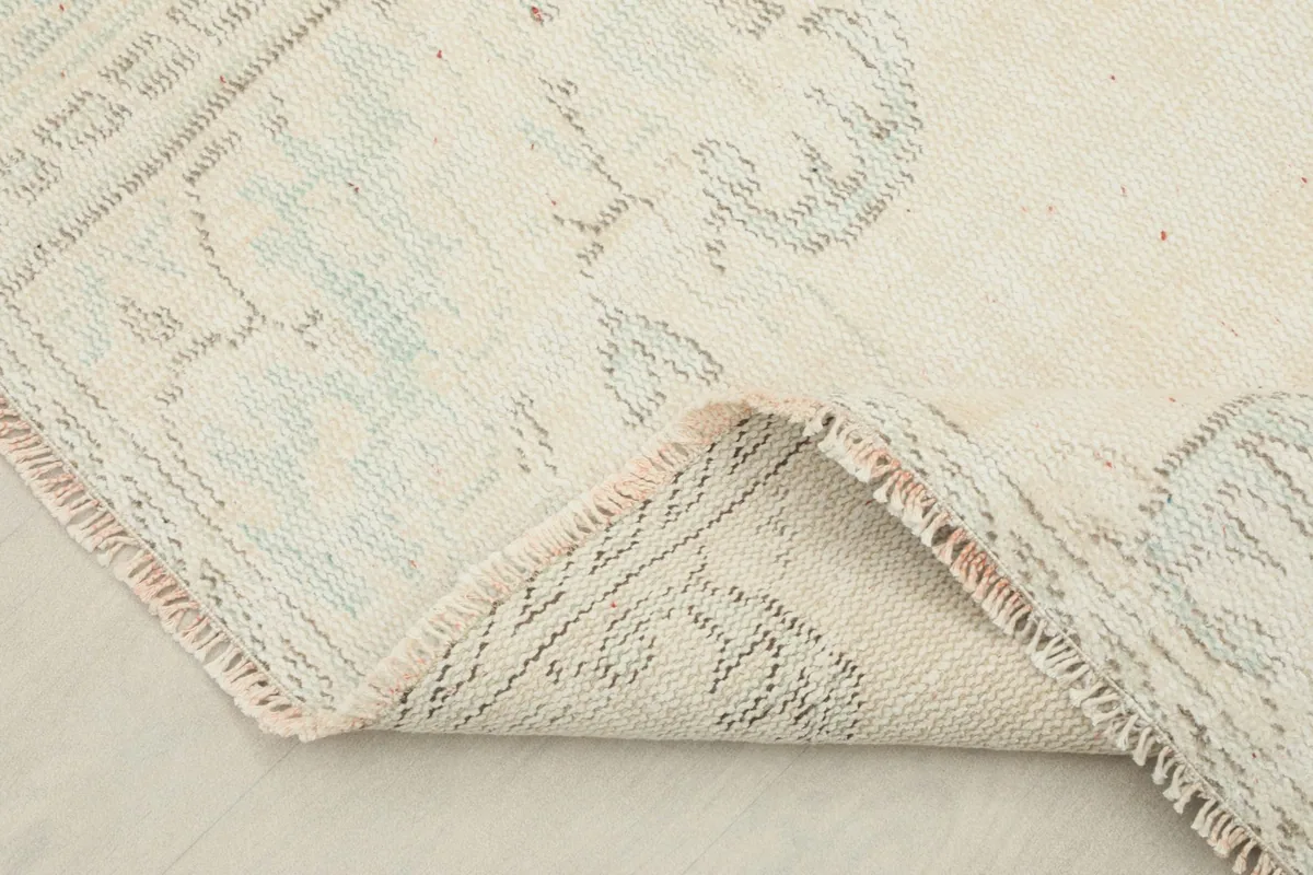 Corner of the rug folded back, revealing the backing and pile thickness