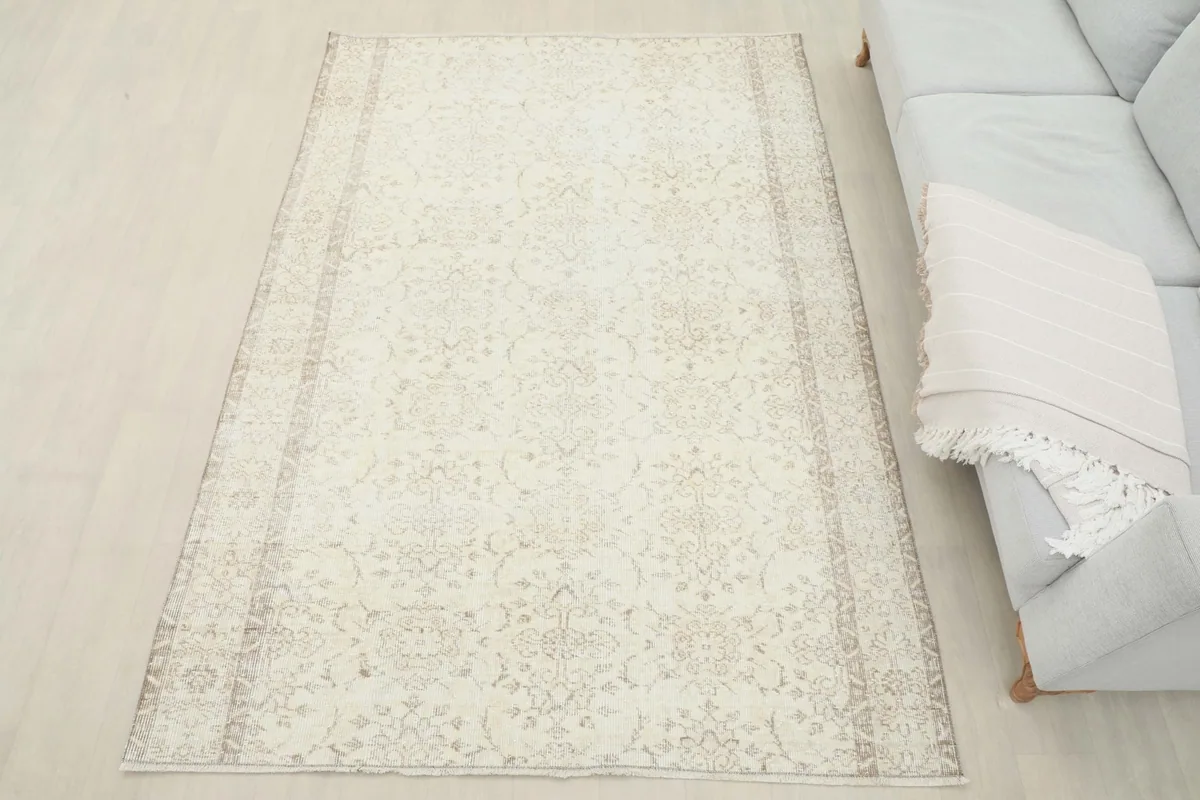 Full view of the ivory and beige vintage rug in a living room setting, complementing the light furniture.