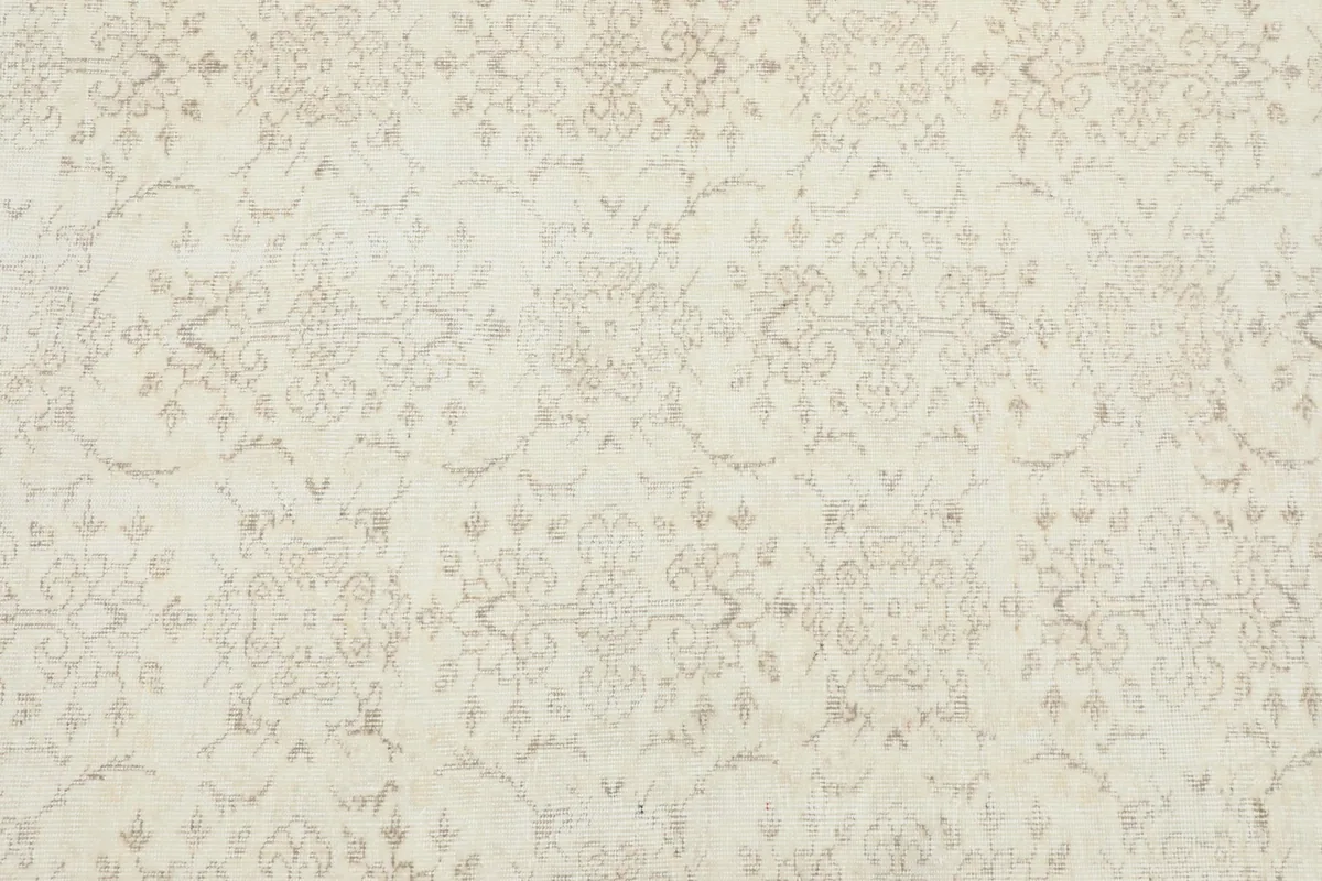Close-up detail of the ivory field with beige floral and geometric motifs, showing the low pile.