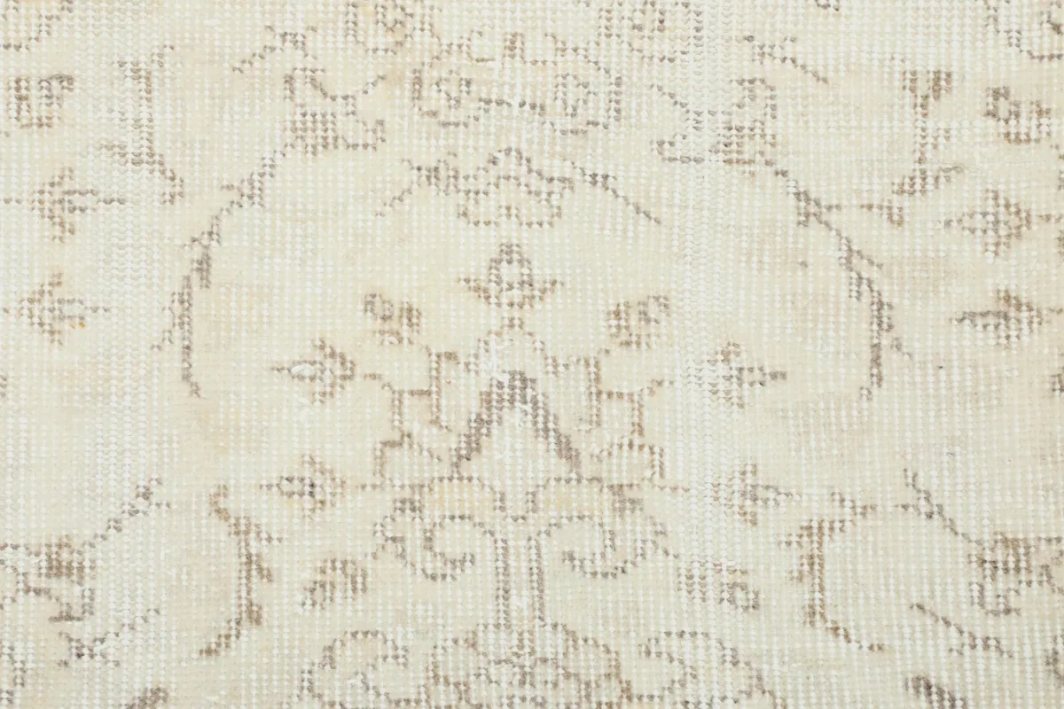 Detailed view of the intricate beige patterns against the ivory background, showcasing the hand-knotted texture.