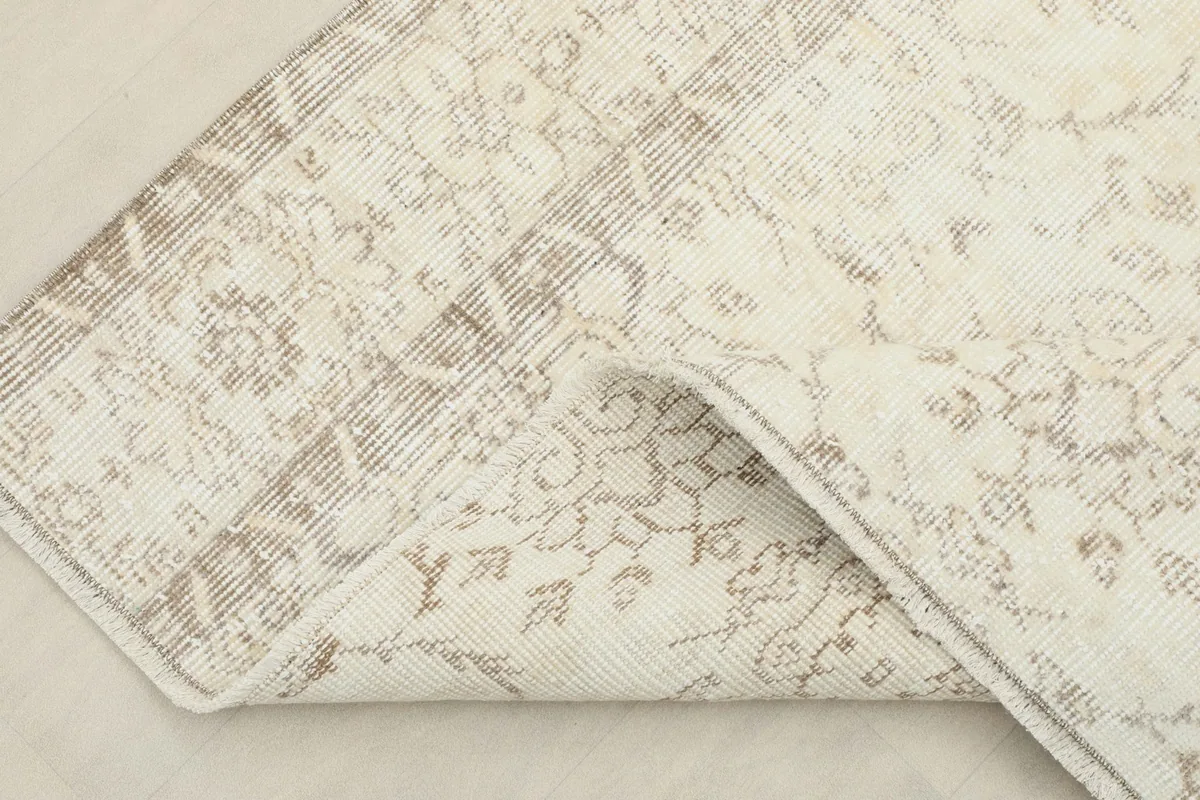 View of the rug folded back to show the cotton foundation and the reverse side of the hand-knotted pile.