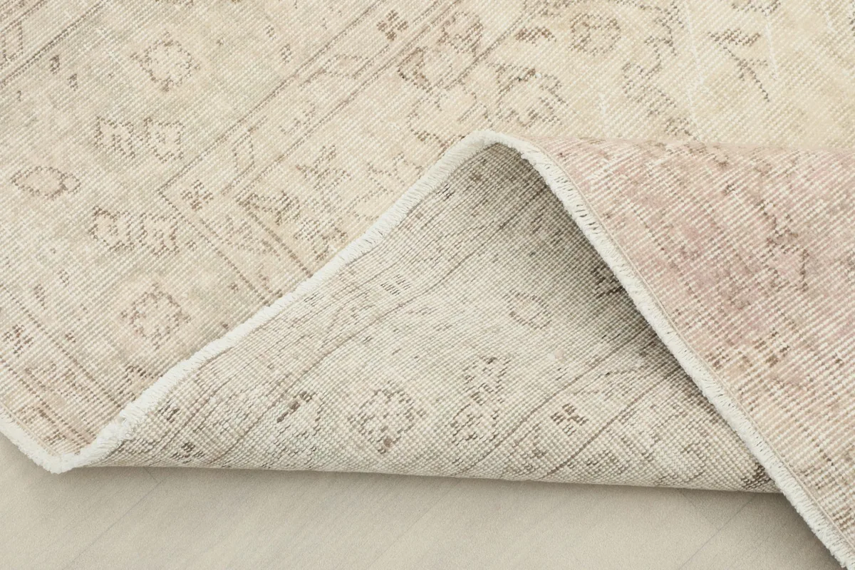 Corner of the rug folded back to show the cotton foundation and the reverse side