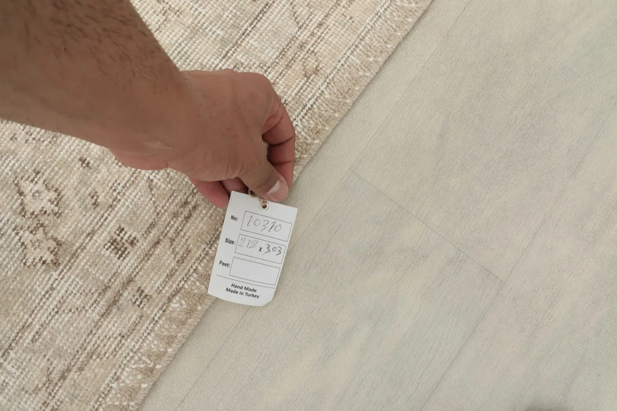 Hand holding a tag with rug details, showing the quality and authenticity of the piece