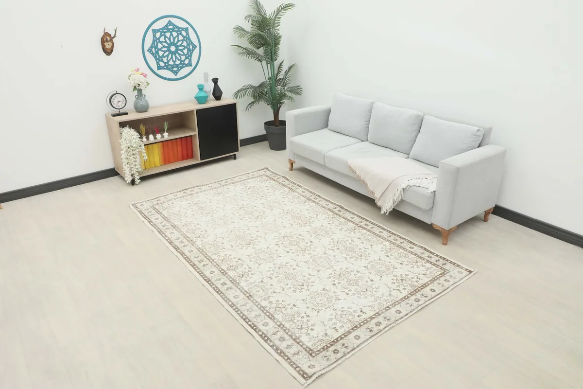Ivory and brown vintage rug placed in a modern living room setting with a light gray couch