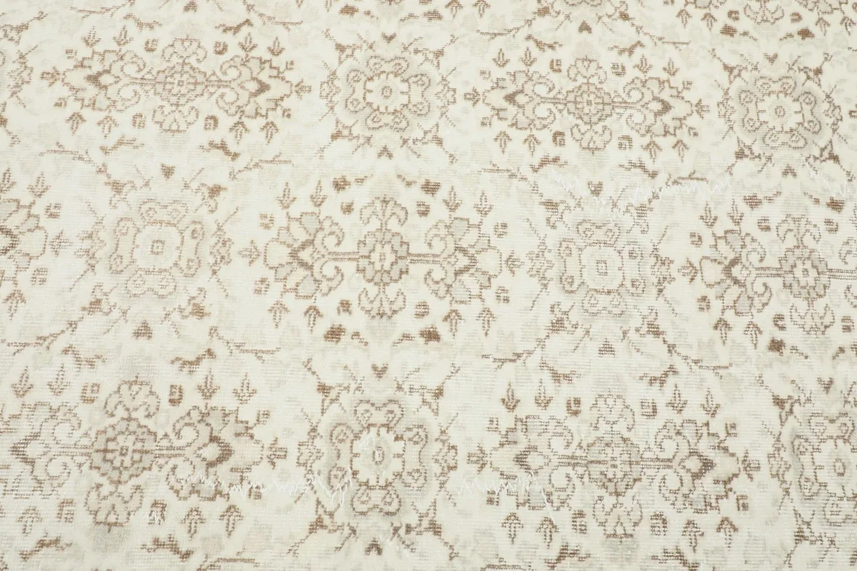 Detailed view of the geometric and floral motifs on the ivory background of the rug