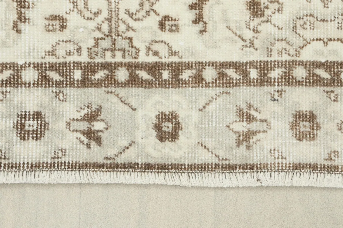 Detail of the rug's brown border and the short, natural fringe
