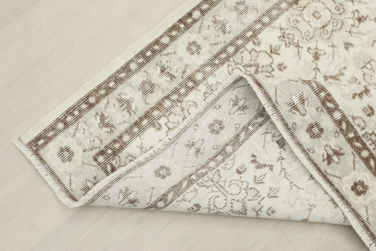 View of the rug folded back, revealing its cotton foundation and hand-knotted construction