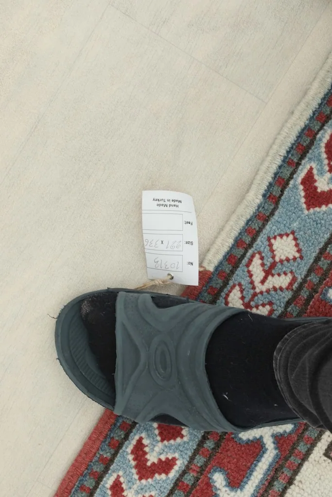 Close-up of the low wool pile texture, showing a foot for scale and a tag
