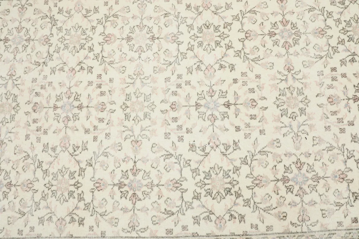Close-up detail of the main field's repeating floral and geometric motifs in ivory, rose, and gray