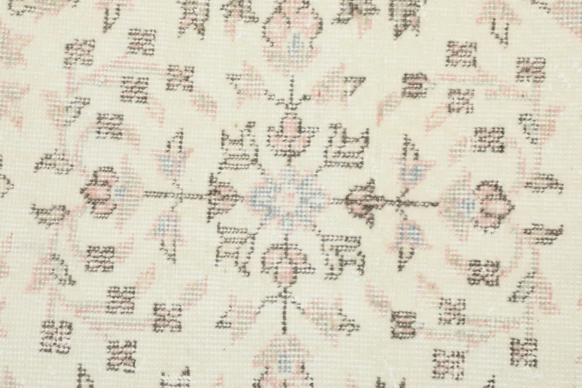 Detailed view of the central floral pattern with subtle blue and rose accents on the ivory field