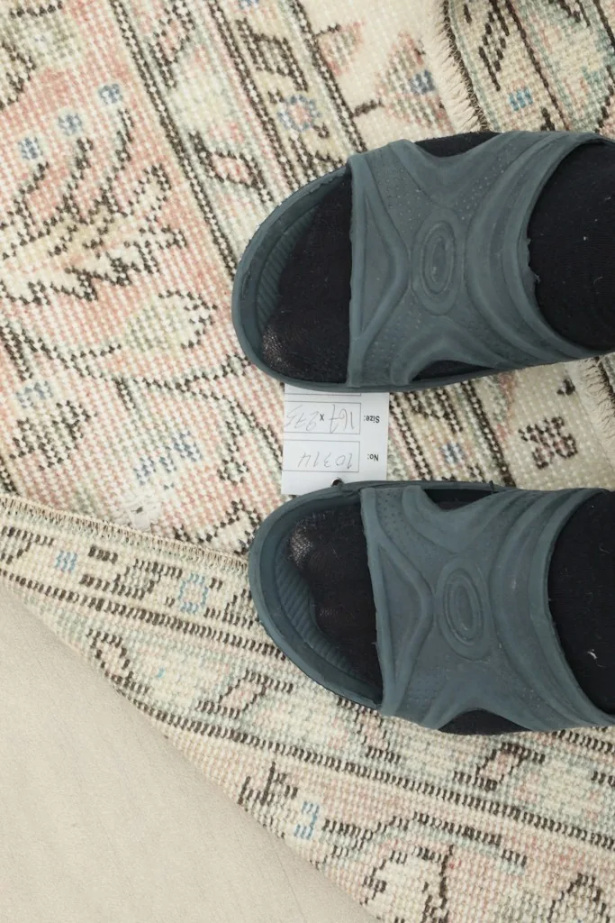 Close-up of the low wool pile texture with a foot for scale, showing the vintage wear