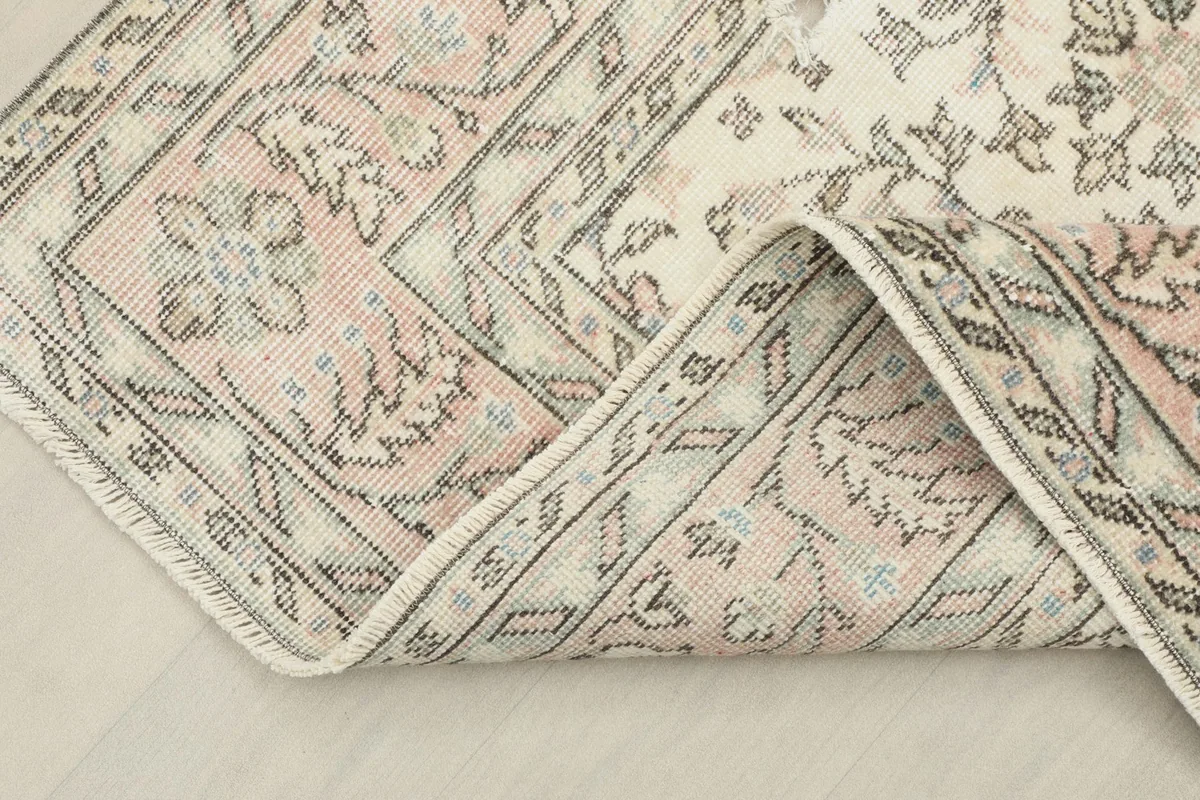 Corner of the hand-knotted rug folded back, showing the wool pile and cotton foundation