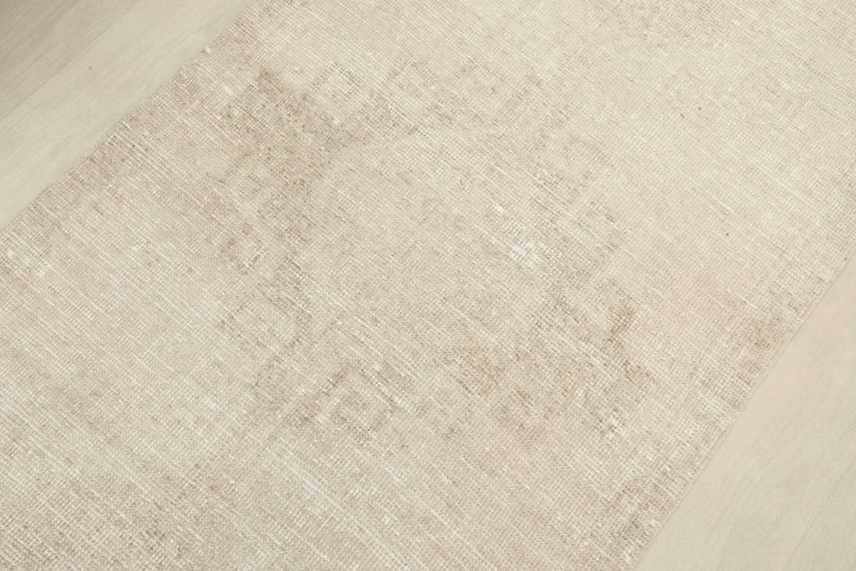 Detailed view of the rug's surface, revealing the faint, muted geometric or tribal motifs and soft wool pile.