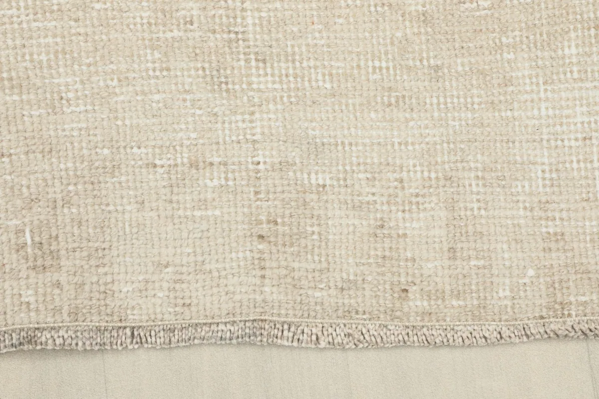 Close-up of the short, natural fringe and finished edge of the vintage beige runner rug.