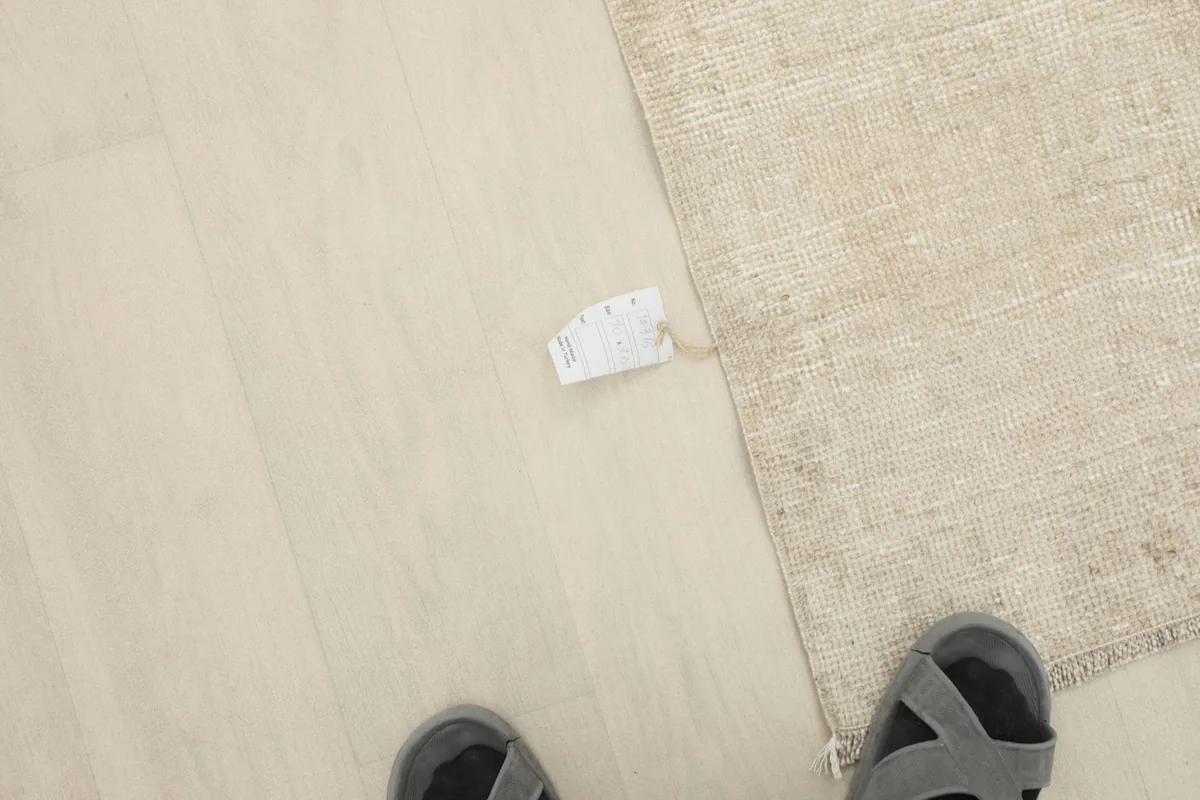 Overhead view of a person's feet next to the runner rug, showing scale and a small tag.