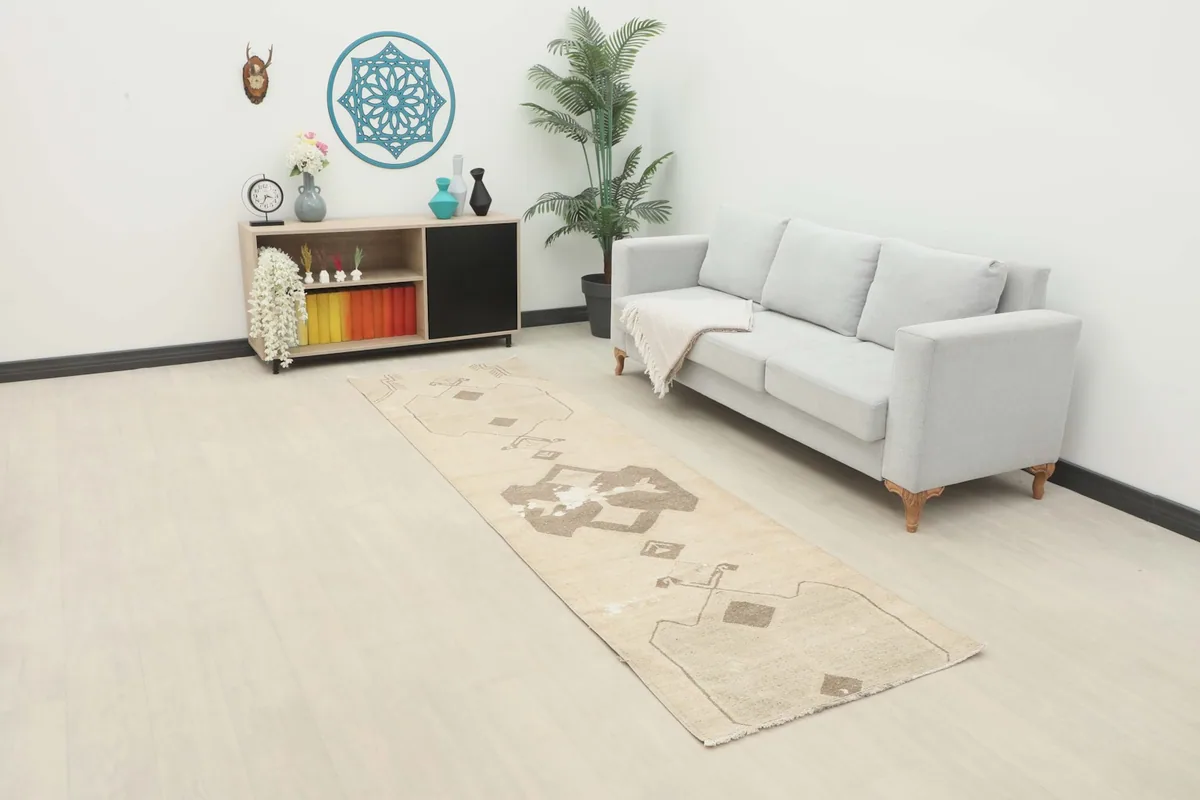 The beige and brown runner rug displayed in a modern living space with a light gray sofa.