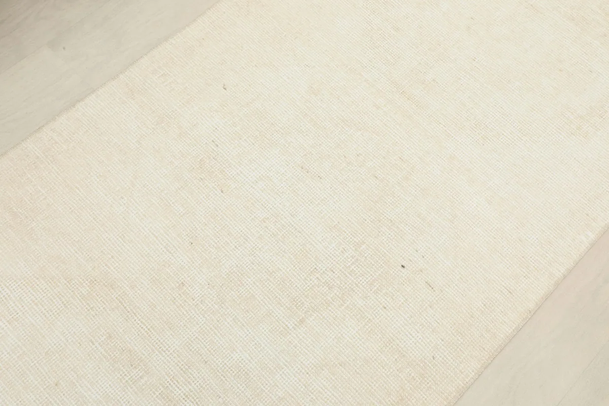 Angled view focusing on the central part of the ivory runner, showing its uniform color and subtle weave.