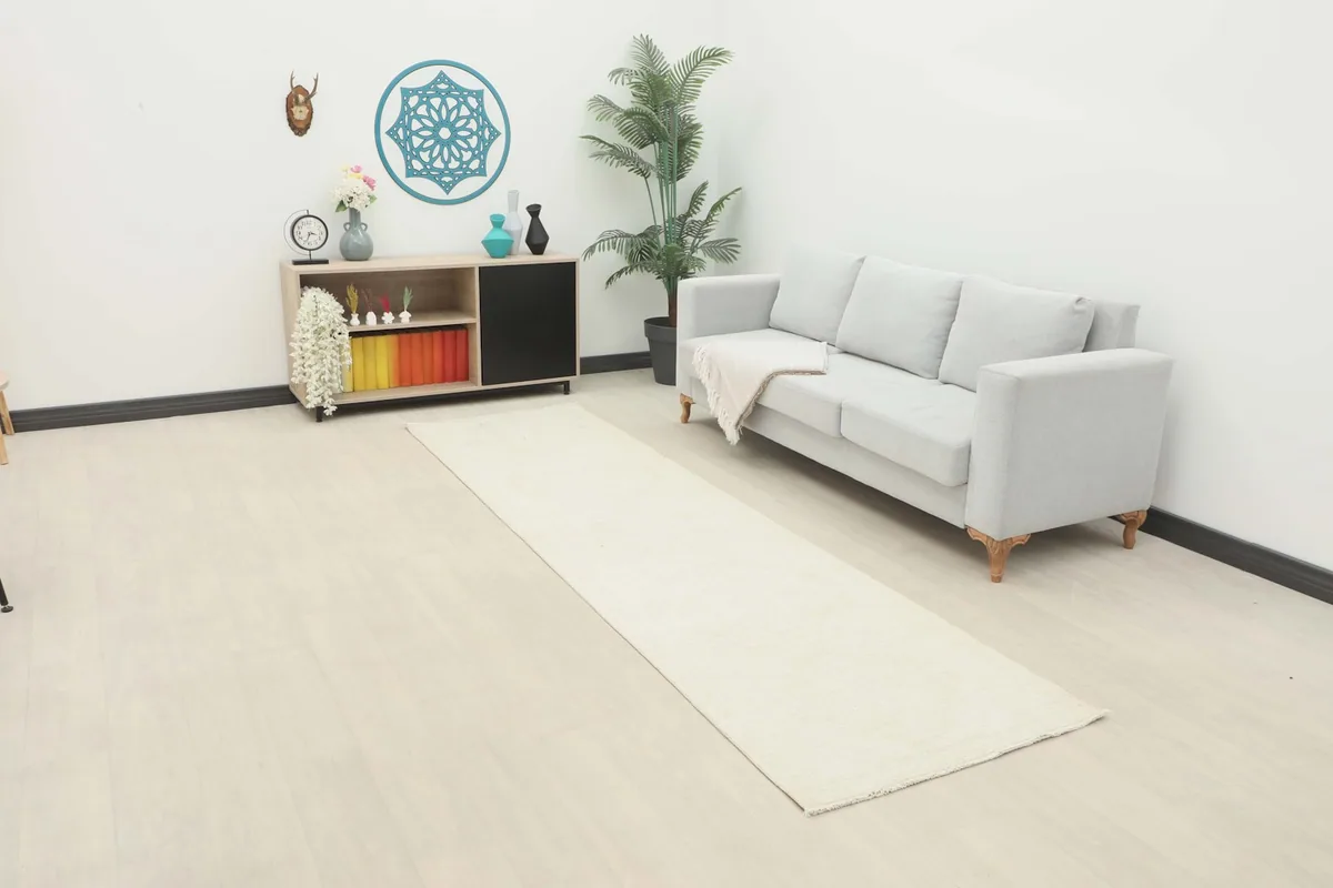Ivory runner rug displayed in a bright room setting with a sofa and minimalist decor.