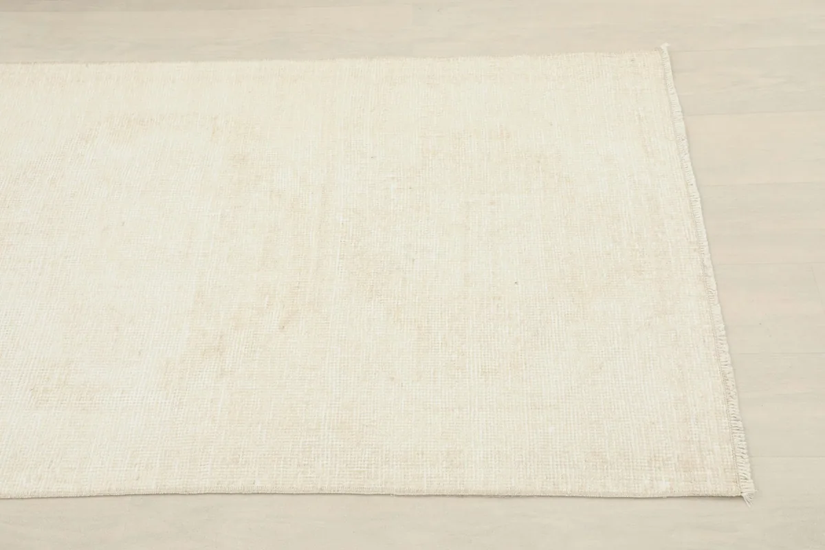 Close-up detail of the ivory wool pile showing subtle texture and a faint geometric pattern.