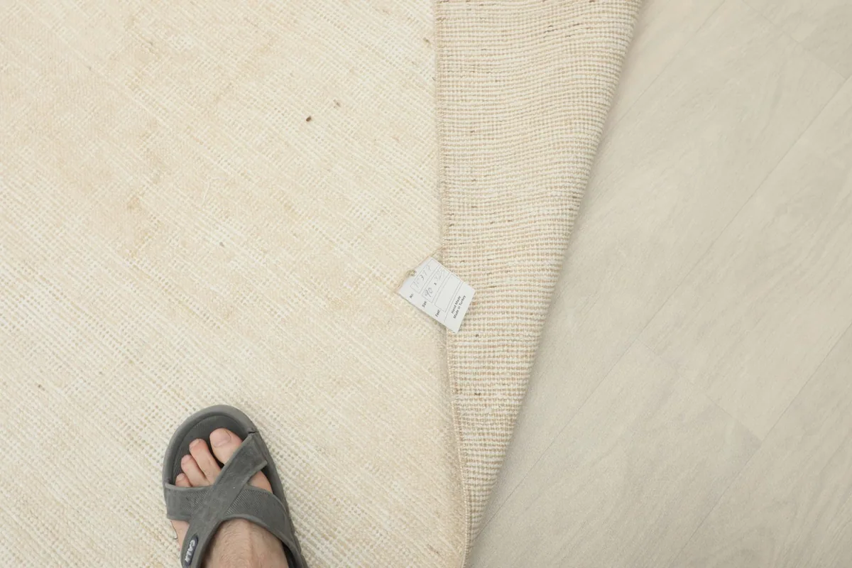 A foot next to the folded rug, indicating scale and showing the back of the rug.