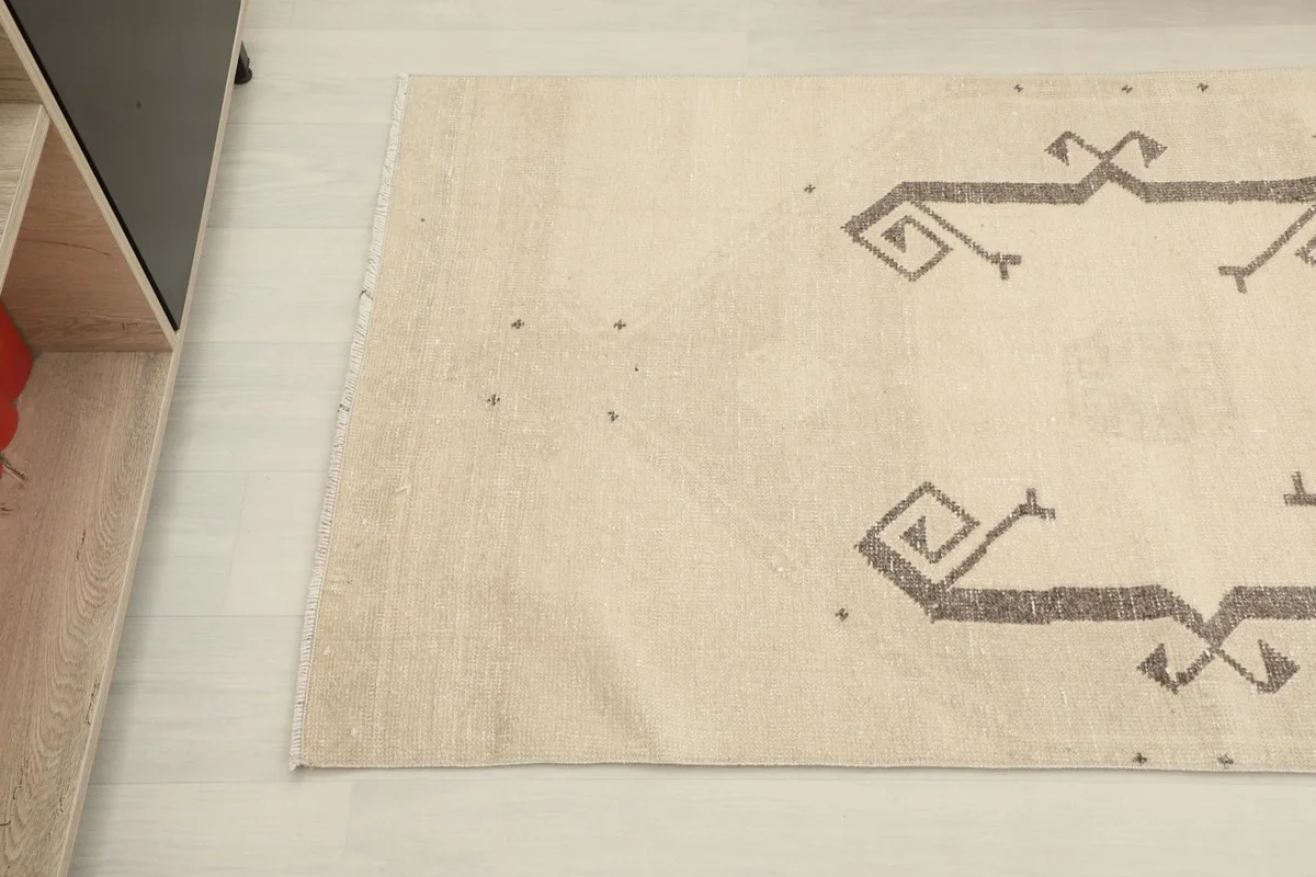 Detailed overhead shot of the rug's surface, highlighting the subtle texture and color variation near a furniture piece.
