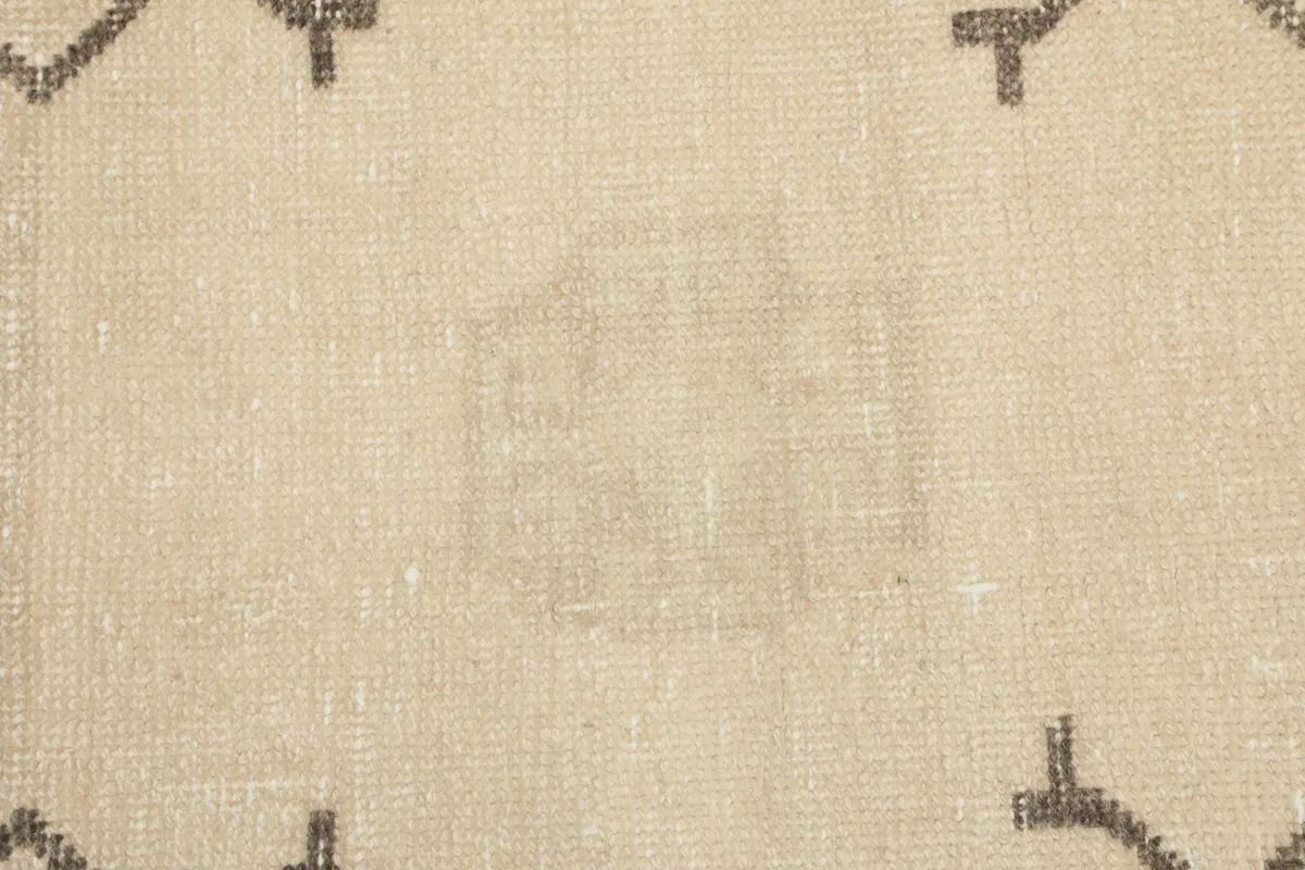 Texture detail of the low wool pile, showing the hand-knotted construction and gentle wear on the ivory surface.