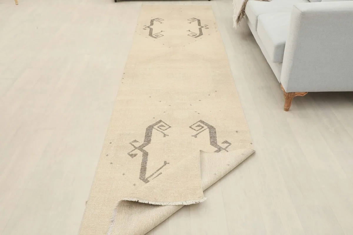 The runner rug partially folded, showcasing its flexibility and the repeat of the gray tribal motifs.