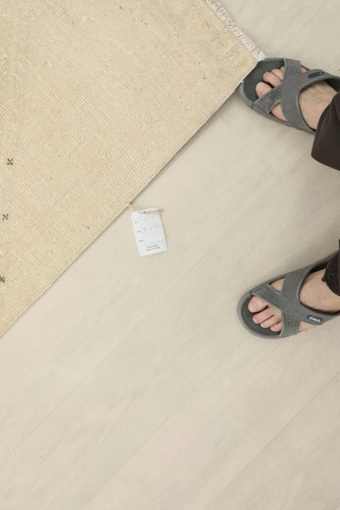 Overhead shot showing a person's feet next to the rug, indicating scale and the rug's placement.