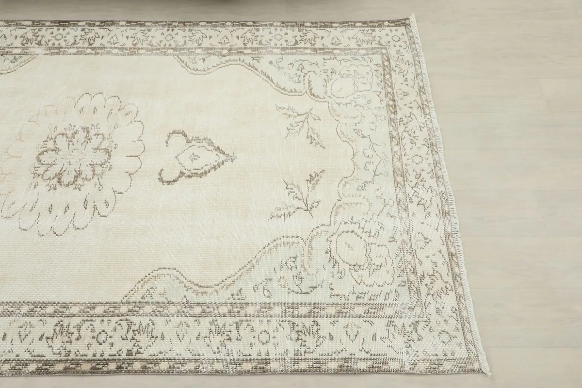 Close-up detail of the rug's corner, showing the gray border patterns and ivory field.
