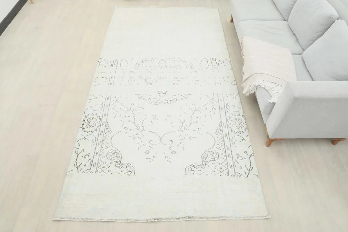 Full view of the 5'3" x 10'0" rug laid out in a room, next to a light gray sofa
