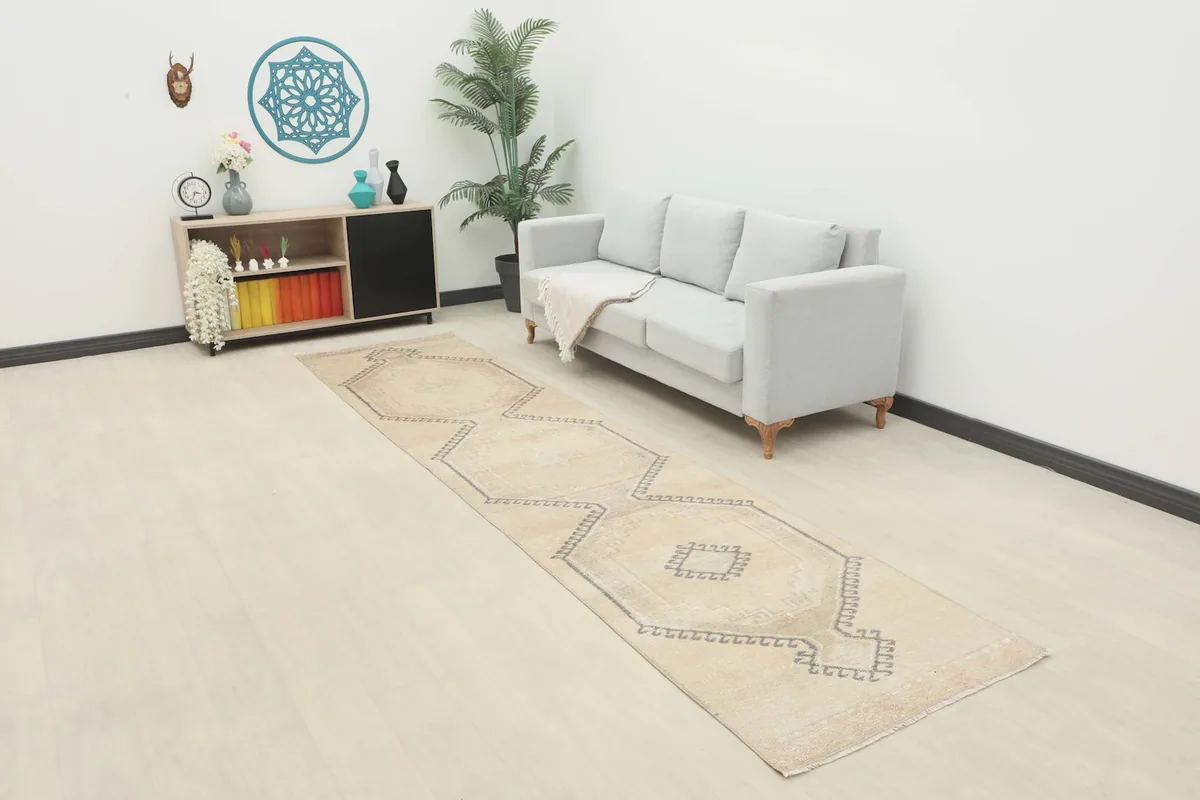 Ivory and gray runner rug placed in a modern living space with a light sofa and minimalist shelving.