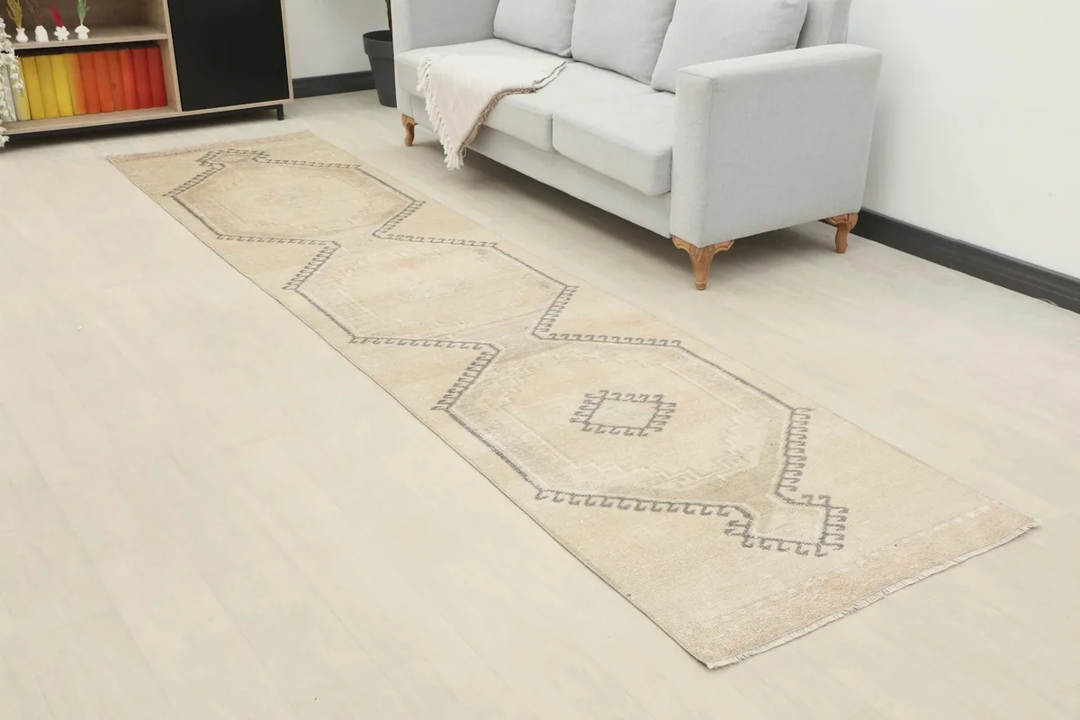 Angled view of the vintage runner rug extending along a hallway next to a light-colored sofa.