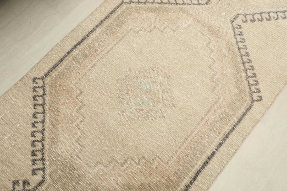 Overhead detail of a central geometric medallion on the ivory runner, showing subtle color variations.