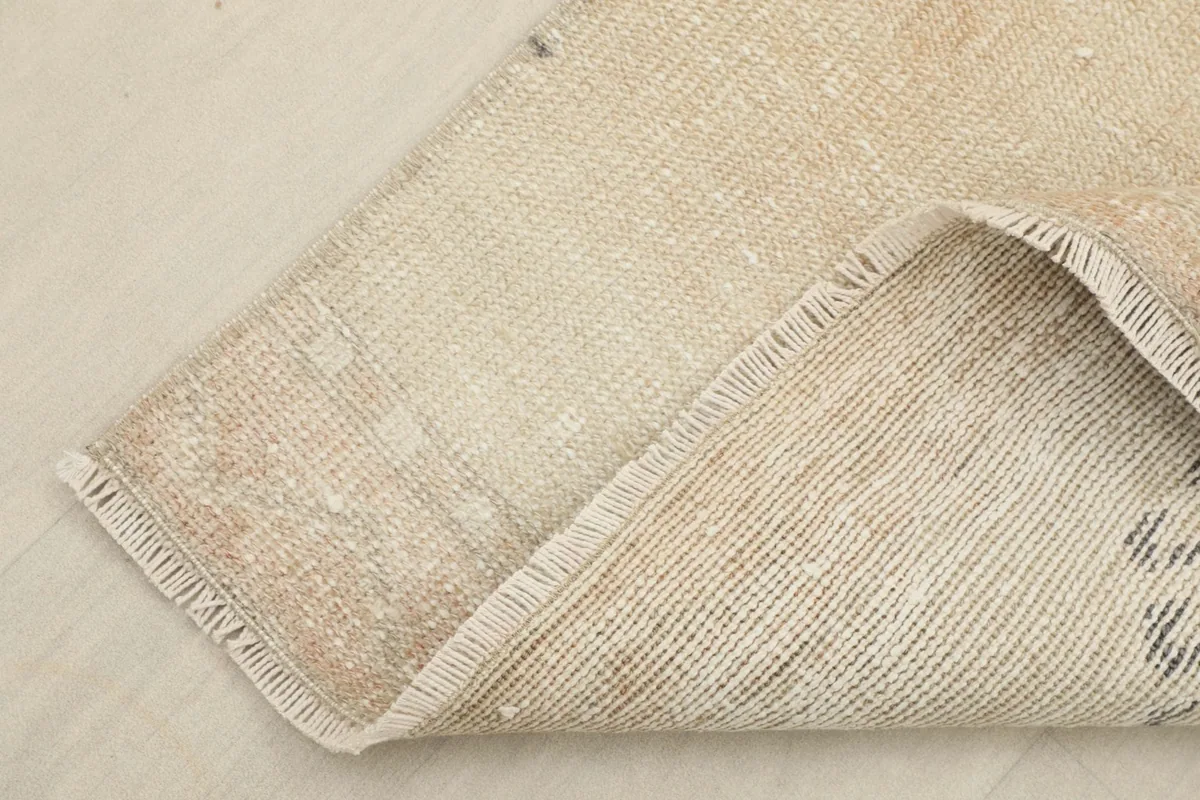 Corner of the runner rug folded to show the hand-knotted cotton foundation and wool pile.
