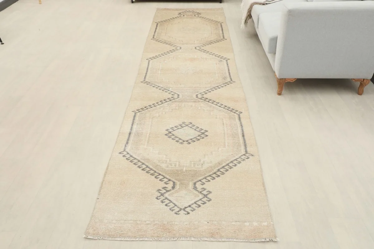 Full overhead view of the ivory and gray geometric runner rug laid out on a light floor.