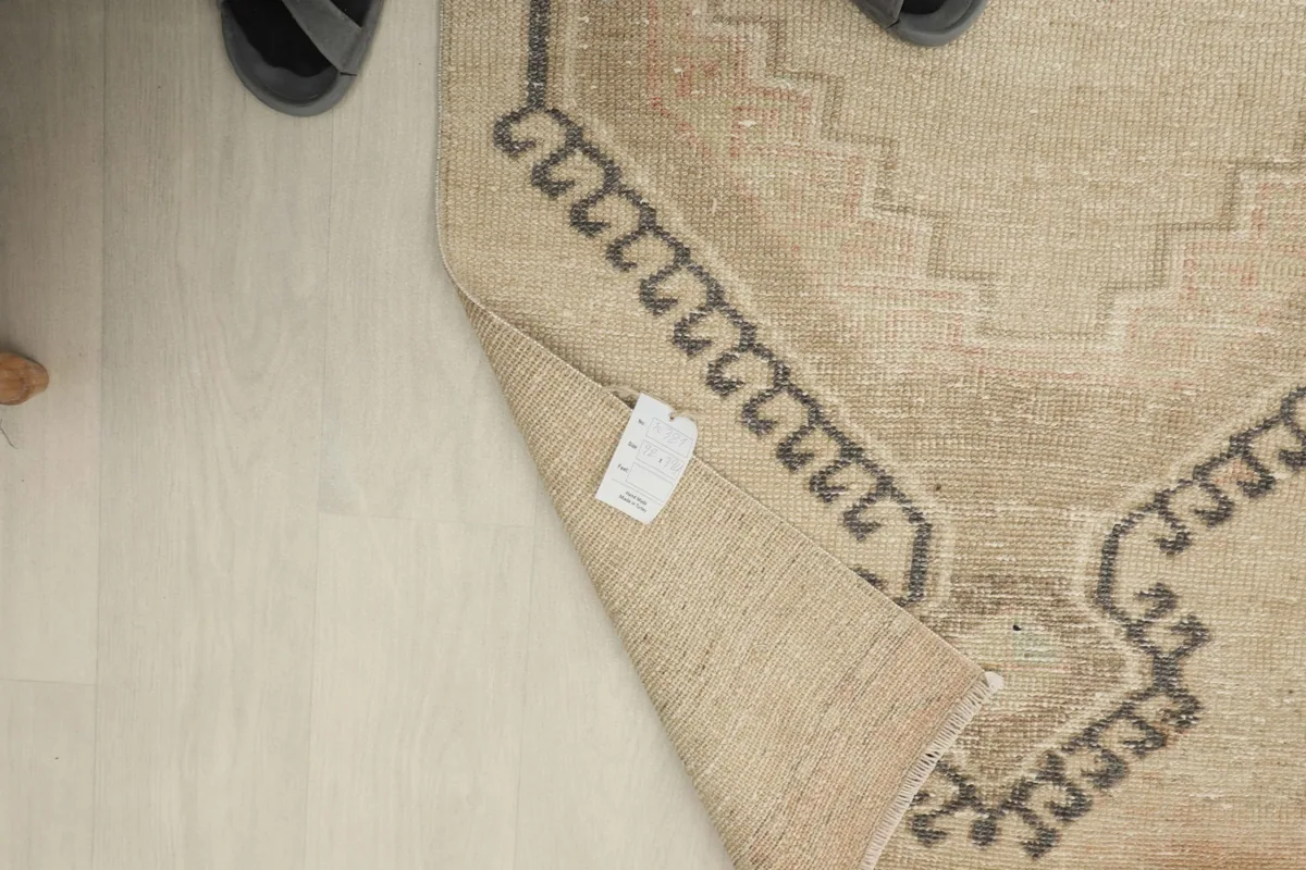 Close-up of the rug's label on the underside, with a person's feet visible nearby.