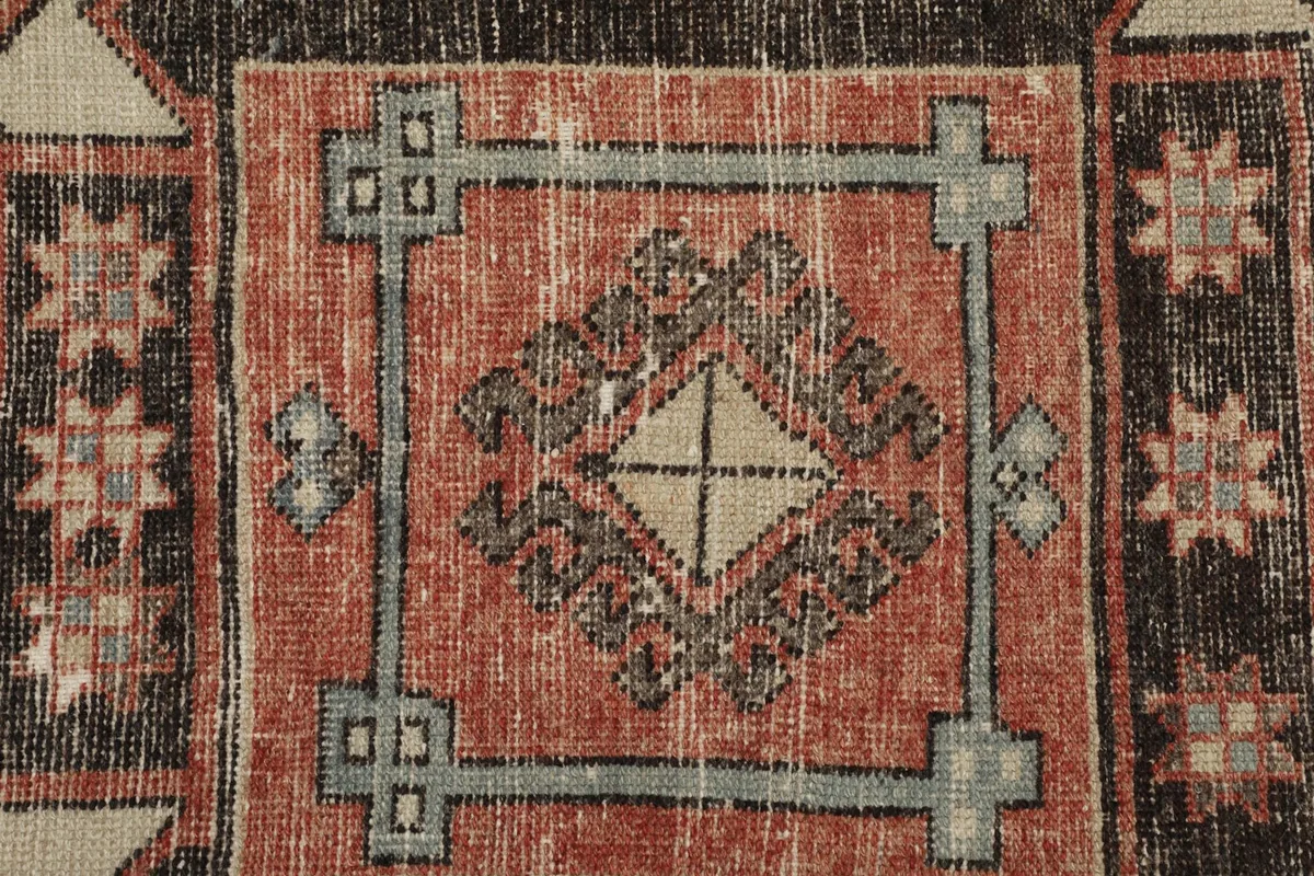 Macro detail of the rug's surface, showing the wool pile texture, colors, and hand-knotted craftsmanship.