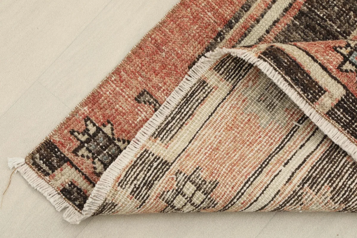 Corner of the rug folded back, revealing the reverse side of the hand-knotted wool pile on cotton foundation.