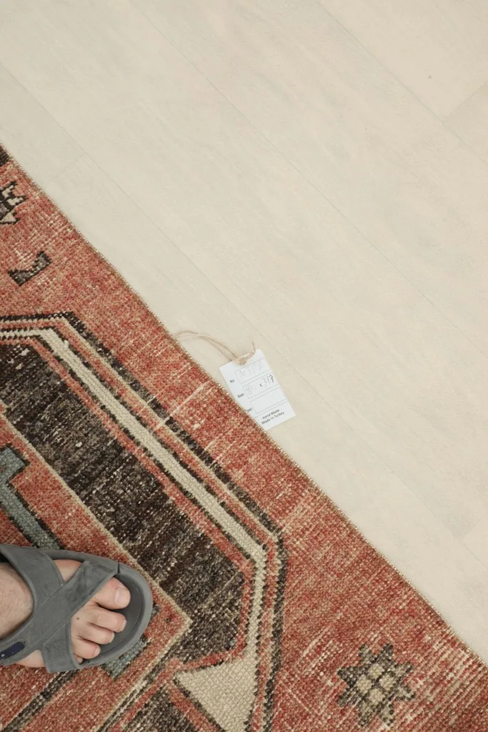Foot resting on the rug, providing a sense of scale and texture for the rust and charcoal runner.