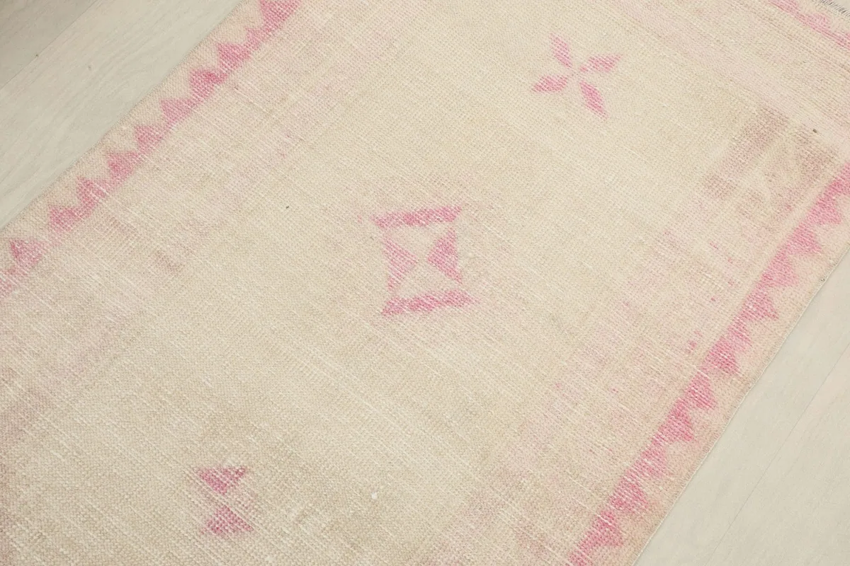 Detail view of the center, showcasing a pink geometric motif on the ivory background
