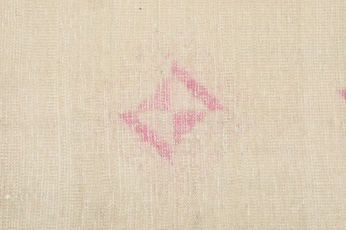 Macro shot of a pink diamond-shaped geometric motif, revealing the wool texture