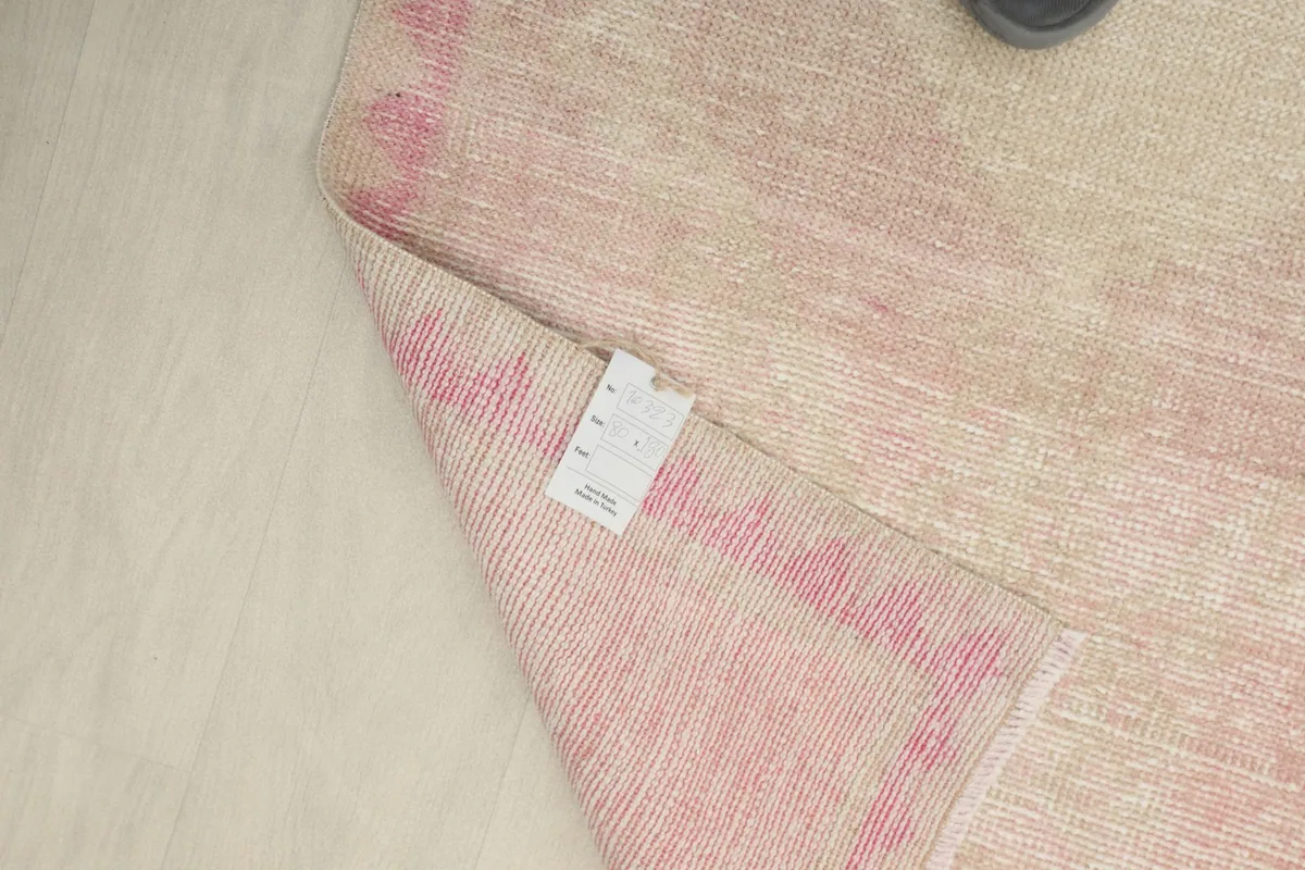View of the rug's back, revealing the woven structure and a product label