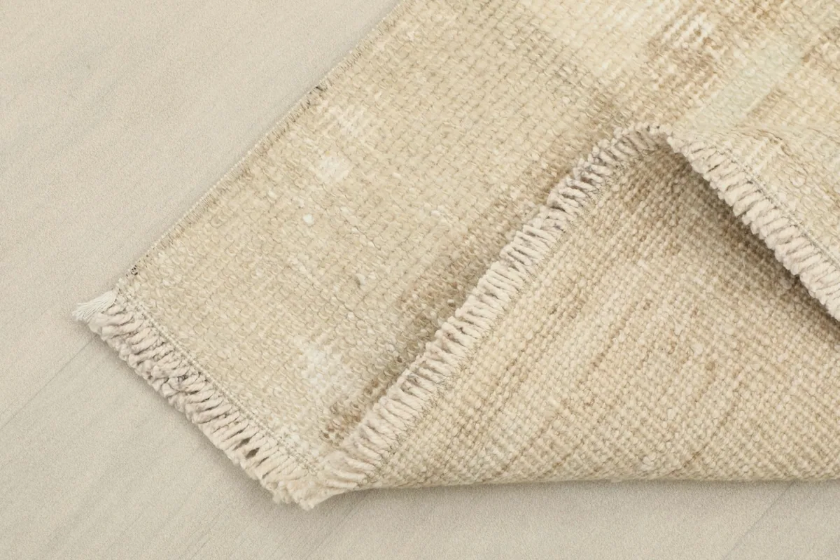 Corner of the rug folded to show the cotton foundation and hand-knotting on the back
