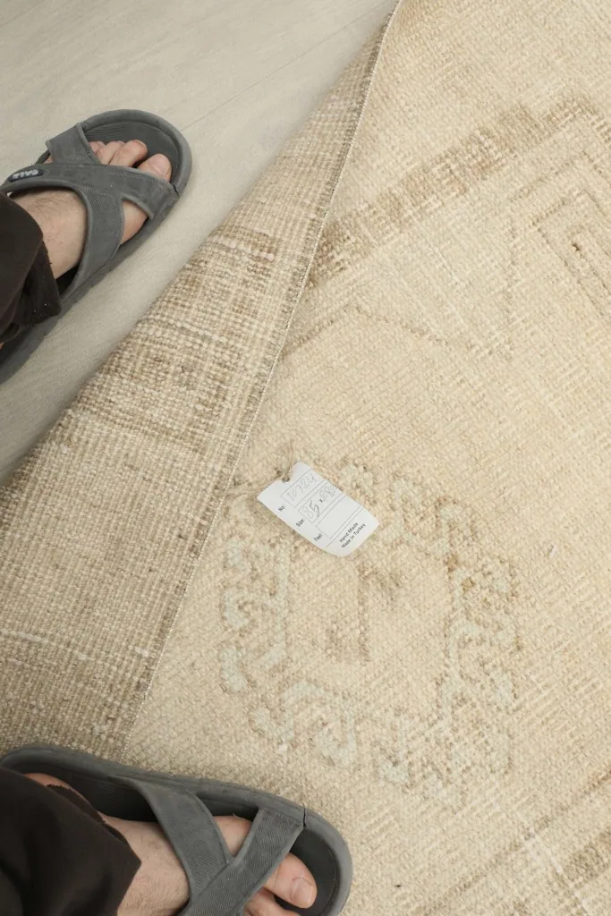 View of the rug with a size tag and feet for scale, showing texture and color