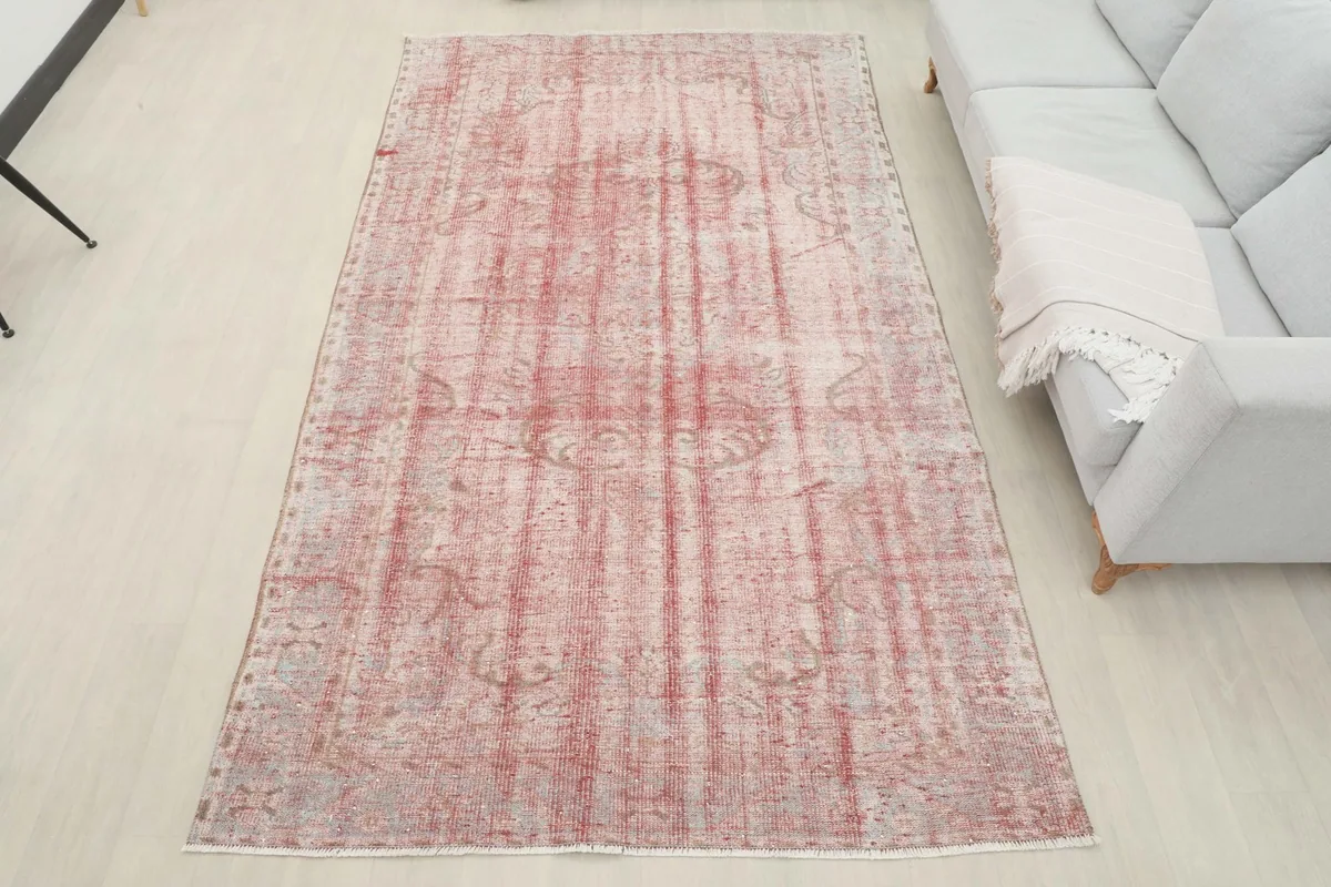 Overhead view of the rose and gray rug placed in a room, showcasing its full size and pattern.